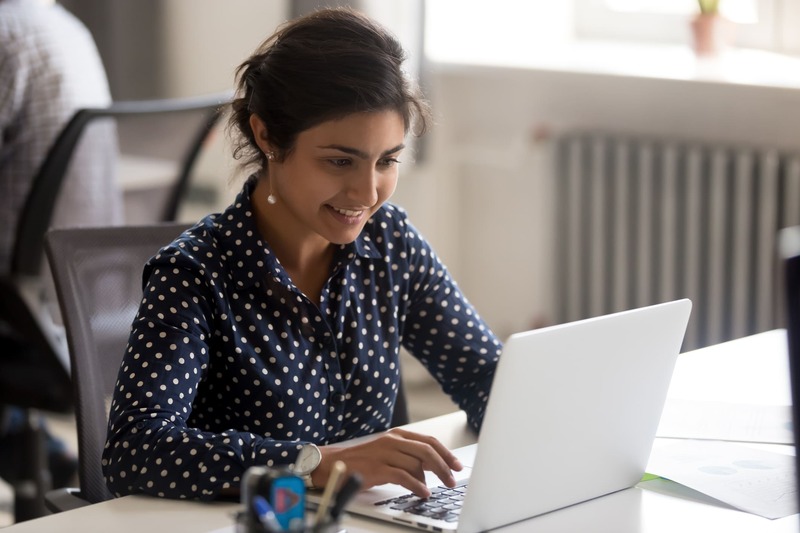 first-aid-course-smiling-indian-female-employee-using-laptop-at-workplace